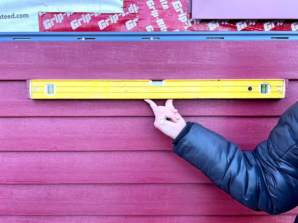 Golden Group Roofing's team member holding up a leveler for home siding. Home Siding Questions to Ask Your Contractor for Your Greater Boston Area Home.