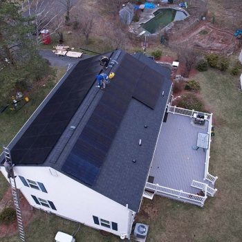 Aerial view of Golden Group workers on a roof installing solar panels on both sides of the slanted roof on a residential home